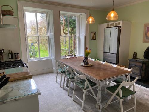 une cuisine avec une table avec des chaises et un réfrigérateur dans l'établissement Beautiful Listed Mansion with incredible woodland views, à Huntly