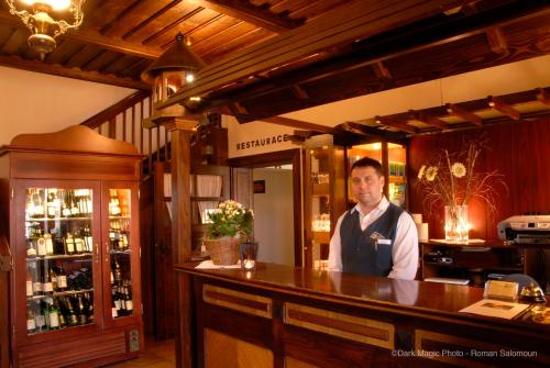 a man is standing behind a bar in a restaurant at Koliba u Cerneho Medveda in Zlín