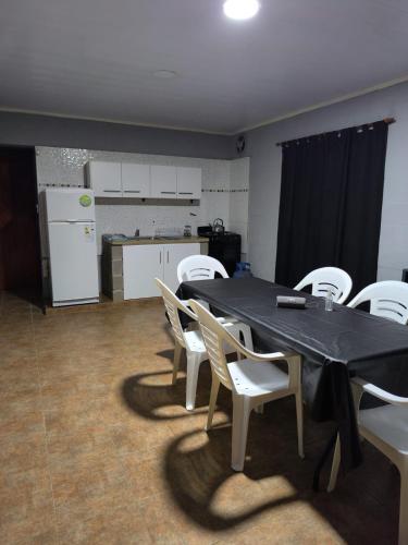 a dining room with a table and white chairs at Quintas Barceló in Baradero