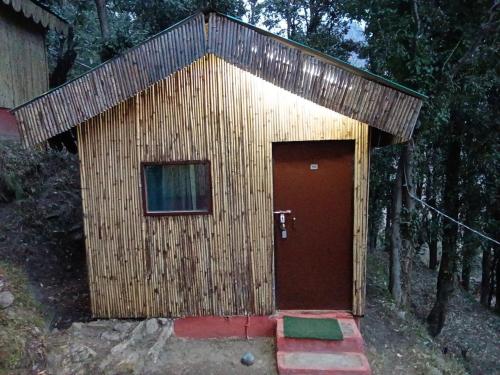 a small wooden building with a red door at TTN - The Trekker's Nest in Joshīmath