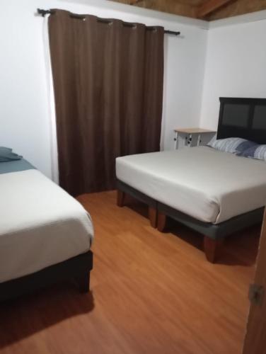 two beds in a room with wooden floors at Refugio el Amparo de Paine in El Majuelo