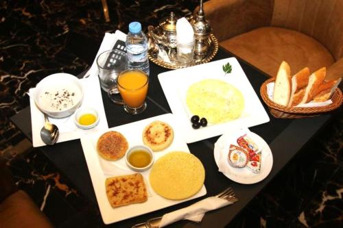 a table topped with plates of food and orange juice at Hotel D'Europe Centre Ville in Kenitra