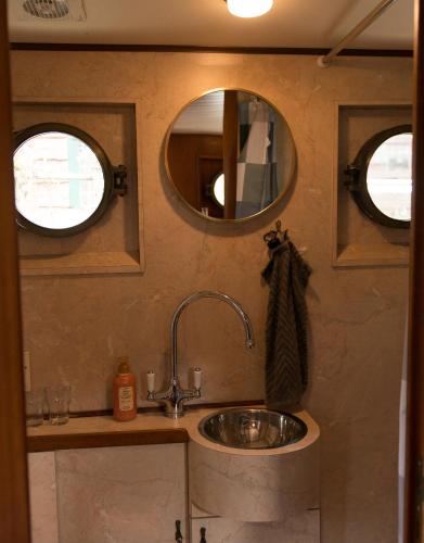 a bathroom with a sink and two mirrors at Salonboot de Wending in Groningen