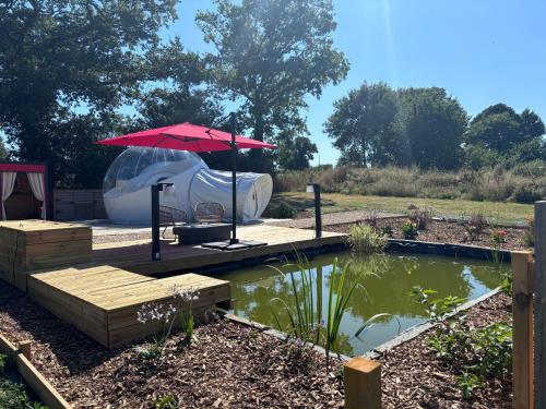 a patio with an umbrella next to a pond at Bubble Jade in Val Couesnon