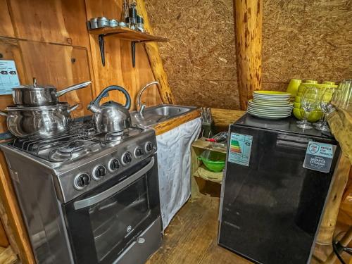 a kitchen with a stove and a sink with pots and pans at Refugio de Montaña Patagonia, pesca, trekking, miradores in Llanada Grande