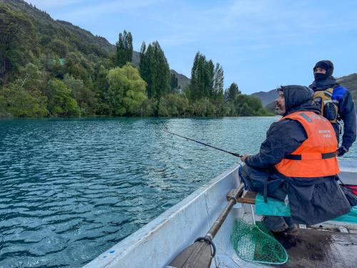 two men in a boat on a river with a fishing pole at Refugio de Montaña Patagonia, pesca, trekking, miradores in Llanada Grande