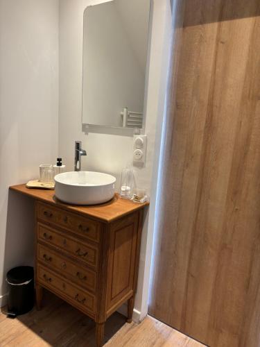 a bathroom with a sink and a wooden dresser with a mirror at La Parenthèse in Régnauville