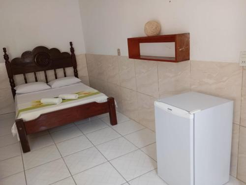 a bedroom with a bed and a small refrigerator at Pousada Iakã Boipeba in Ilha de Boipeba