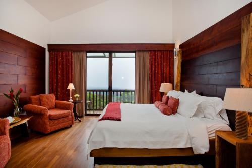a bedroom with a large bed and a balcony at Poas Volcano Lodge in Vara Blanca