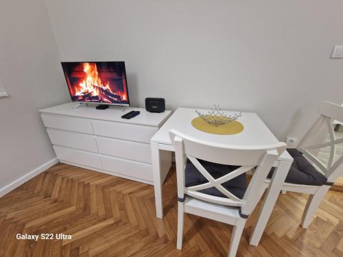 a small white table and chairs in a room with a tv at Park Oaza in Čačak