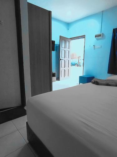 a white bed in a blue room with a door at Kamar Musafir MMS in Ipoh