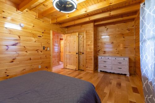 a log cabin bedroom with a bed and wooden walls at Cozy Canopy in Stanton