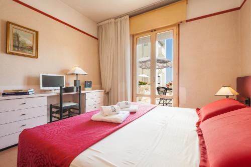 a bedroom with a bed with a desk and a window at Hotel Ca' Di Valle in Cavallino-Treporti