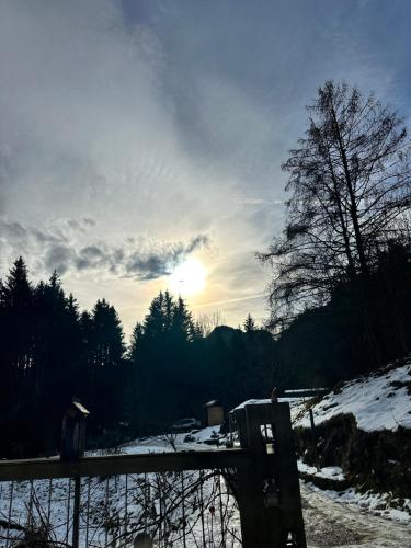 a bench in the snow with the sun in the sky at Bauwagen mit Bergblick in Bad Reichenhall