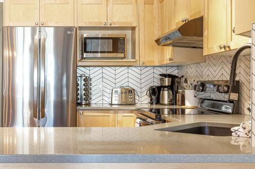 a kitchen with wooden cabinets and a stainless steel refrigerator at Alpine at The Lodges of Canmore in Canmore