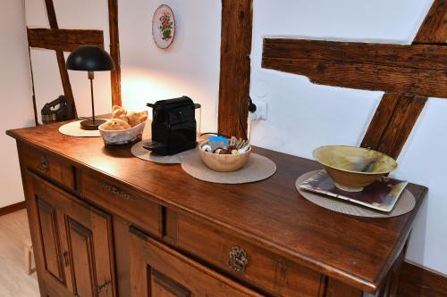 a wooden cabinet with bowls of food on top of it at Gîte Entre Vignes et Vergers maison historique in Gueberschwihr