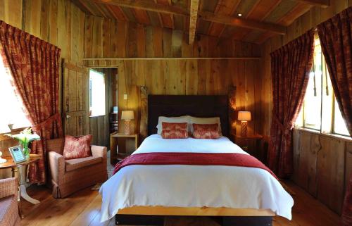a bedroom with a bed and a chair and windows at Poas Volcano Lodge in Vara Blanca