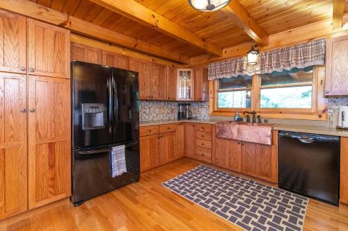 a kitchen with a black refrigerator and wooden cabinets at Mill Creek Point in Rogers