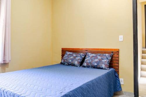 a bedroom with a bed with a blue blanket and pillows at Royal Bela Vista in Rio das Ostras