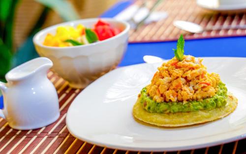 a white plate with a sandwich and a bowl of fruit at Casa Lorenza Hotel in Cartagena de Indias