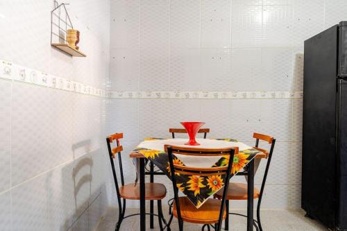 a table with four chairs and a vase on it at Royal Bela Vista in Rio das Ostras