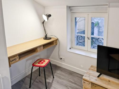 a red stool in a room with a desk and a television at Appartement cosy cœur d'Aurillac, 2 lits, Wifi in Aurillac