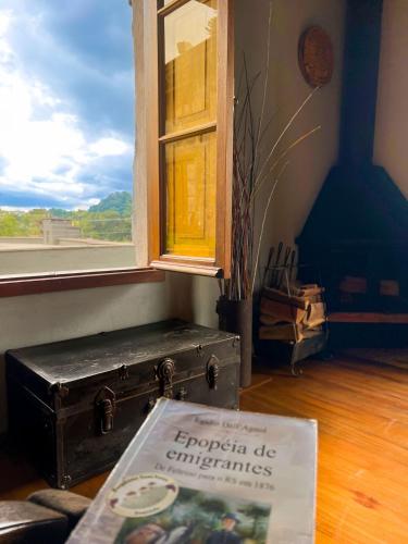 an old trunk sitting on the floor next to a window at Pousada Borghetto – Charme e Exclusividade no Vale dos Vinhedos in Bento Gonçalves