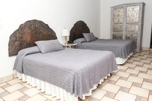 a bedroom with two beds with gray covers and a tile floor at Hotel Boutique Naura Centro in Oaxaca City