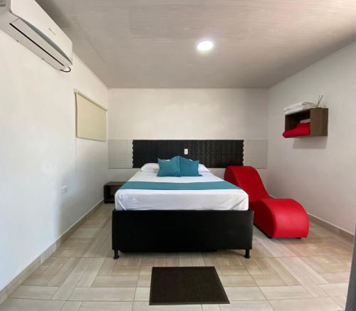a bedroom with a bed and a red chair at Finca Hotel Relax San Jerónimo in San Jerónimo