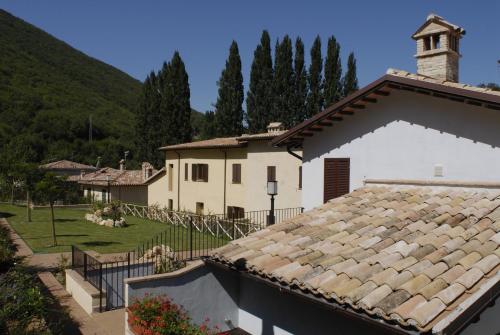 a white house with a roof and a church at Guesia Village Hotel e Spa in Foligno
