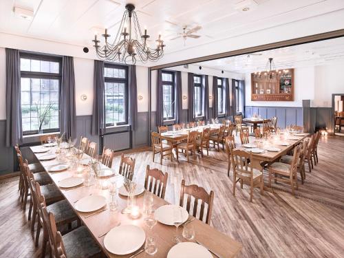 a dining room with tables and chairs and windows at Hotel Everswinkel in Everswinkel