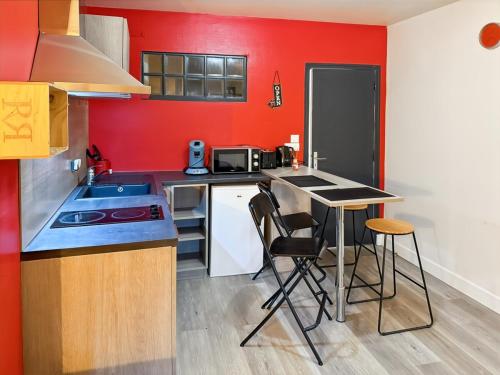 a kitchen with red walls and a counter with stools at Appartement Le Puy Courny, 2 lits, 28m2, wifi in Aurillac