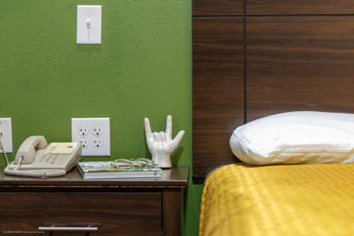 a bedroom with a bed and a phone on a table at Texas Bungalows Hotel & Hotel Que at Lakeline Austin Cedar Park in Cedar Park