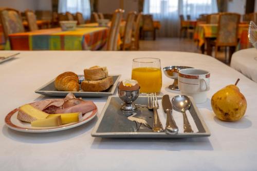a table with two plates of food and a glass of orange juice at Logis Hotel Restaurant Le Faudé in Lapoutroie