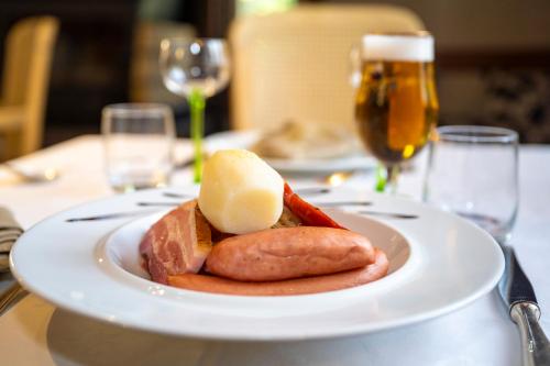 a plate of food on a table with glasses of beer at Logis Hotel Restaurant Le Faudé in Lapoutroie