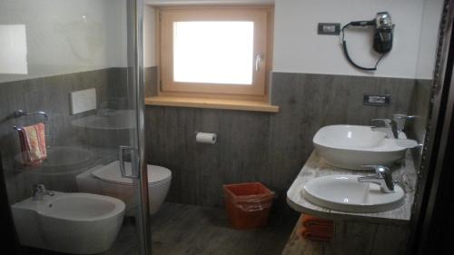 a bathroom with two sinks and a toilet and a window at Lucas Haus in Livigno