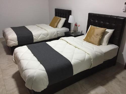 two beds in a hotel room with white and black at Tunaib Plaza in Aţ Ţunayb