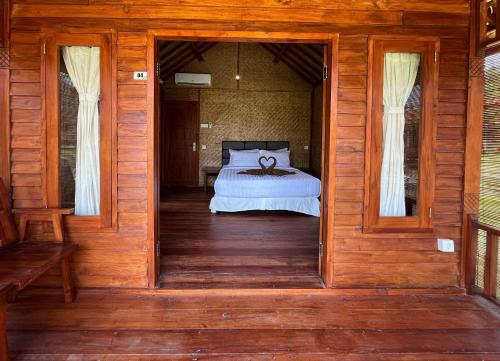 a bedroom with a bed on a wooden floor at Mio Villa Tomang Omang Lombok in Selong Belanak