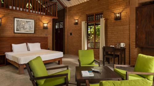 a bedroom with a bed and a table and chairs at Ududola Rainforest Cottages in Migahatenna