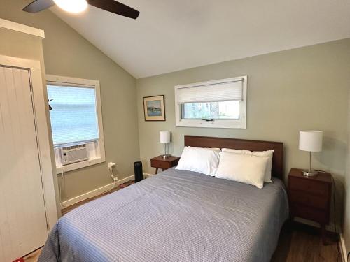 ein Schlafzimmer mit einem Bett und zwei Fenstern in der Unterkunft Sunrise Cottage in Alton Bay