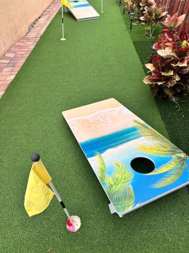 an umbrella and a golf club on the grass at South Florida Spacious Oasis 4BR Retreat with 2 King Beds, Amazing Pool, near Beaches in Deerfield Beach