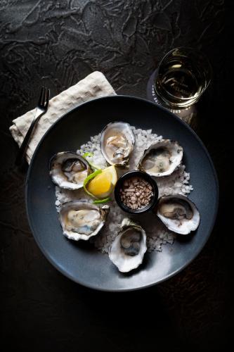a plate of oysters on a table with a glass at Avenue Hotel Canberra in Canberra