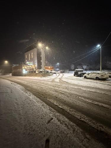 a snow covered street at night with cars parked at Rooms & Spa BJELASICA in Bijelo Polje