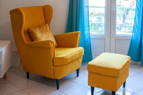 une chaise jaune et un tabouret dans une pièce dans l'établissement Beautiful & large sea view apartment, à Menton