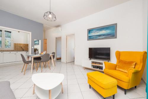 un salon avec une chaise jaune et une télévision dans l'établissement Beautiful & large sea view apartment, à Menton