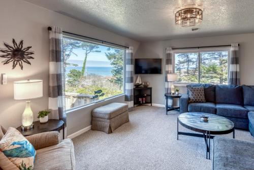 a living room with a blue couch and a large window at The Pacific Lookout Sleeps 6, Hot Tub, Pet Friendly, Ocean View, EV Charger in Lincoln City
