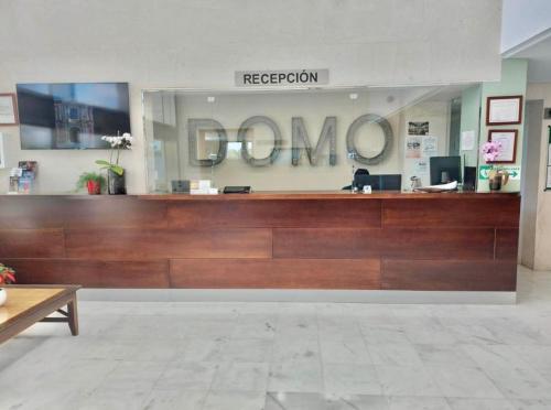 a lobby with a reception desk and a sign that reads foreclosure at ApartHome Domocenter in Bormujos
