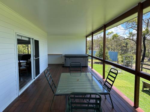 a screened in porch with a table and chairs at Kangaroo hill in Sussex inlet