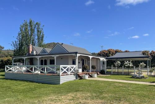 a white house with a fence in the yard at Yarra Fox Farm Cottage Farmstay in Dixons Creek