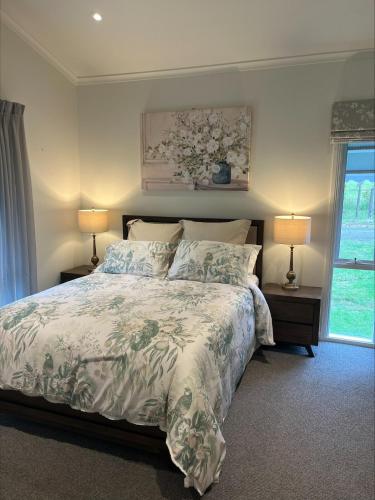 a bedroom with a bed and two lamps on tables at Yarra Fox Farm Cottage Farmstay in Dixons Creek